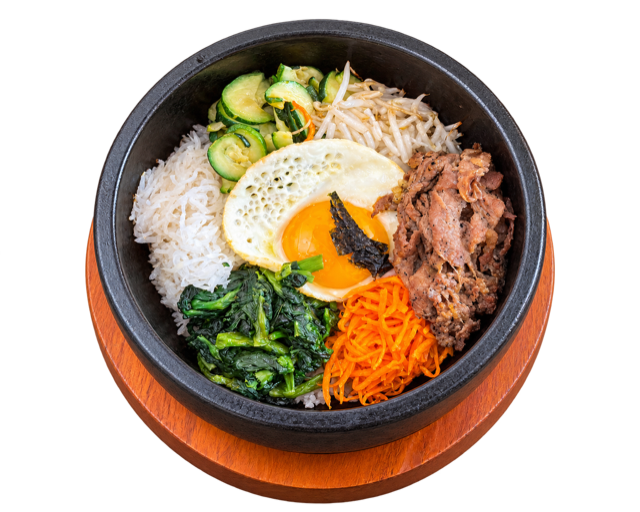 Bi Bim Bop with sliced beef, white rice, vegetables and a fried egg in a black stone bowl