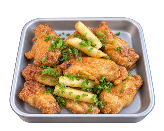 Garlic & Jalapeño chicken wings with rice cakes and chopped green garnish on a metal tray