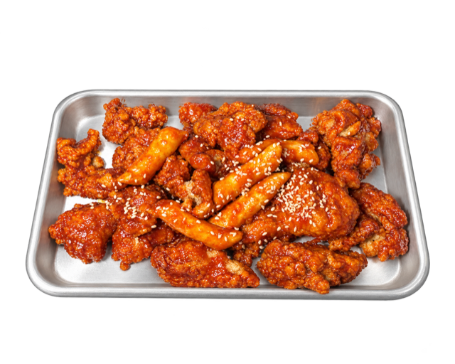 Yang Nyum chicken and rice cakes in a red glaze, topped with sesame seeds on a metal tray